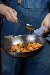 A chef is frying shrimp in a frying pan