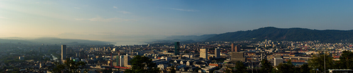 Fototapeta na wymiar Large panorama of the city of Zurich in the morning with a blue sky from the Waid. With Prime Tower, Uetliberg and Lake Zurich. 
