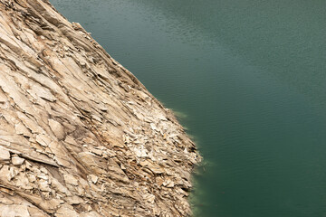 Rock cliff protrudes into the clear water. Natural background