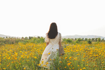 Fototapeta premium A woman standing on a yellow flower field