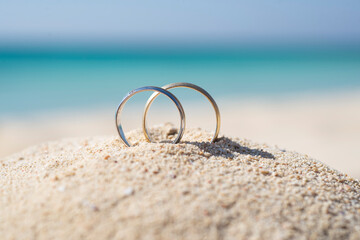 Fototapeta na wymiar Pair wedding rings in sand on tropical beach