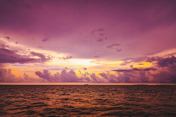 Beach sand, sea and blue sky with clouds. Nature in twilight period which including of sunrise over the sea and the nice beach. Summer beach with blue water and purple sky at the sunset.	