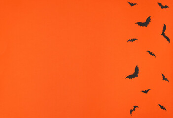 Halloween concept. Black paper bats on orange background. Greeting or invitation card. Flat lay style with copy space. Top view