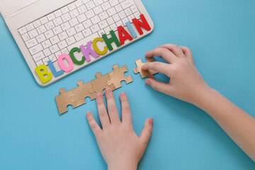 Education. Blockchain for kids. Game Finance. Children hand moves puzzle, laptop on blue background. Mining or blockchain technology. Decentralized Finance