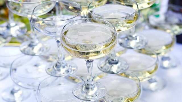 Close-up view 4k stock video footage of many transparent wineglasses full of cold sparkling champagne drinks. Holiday cocktail party reception