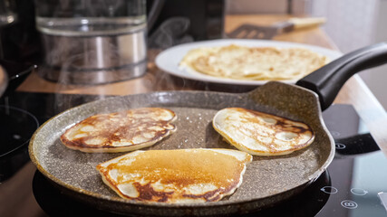 Close-up of mini pancakes on a hot frying pan.