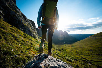 Successful woman backpacker hiking on sunset alpine mountain top
