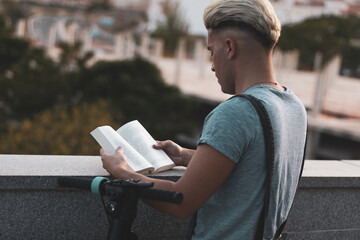 A gay boy parks his scooter to read a book to relax from his anxiety.
LGTBI