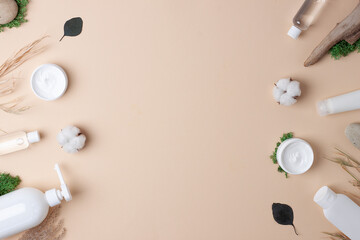 Cosmetic skin care products with flowers and wood on pastel beige background. Flat lay, copy space