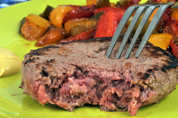 Steak haché avec des poivrons cuits servis dans une assiette en gros plan