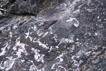 texture of a dark gray stone with white and yellow-orange splashes. Texture mountain close up. Background for wallpaper on the phone, computer with the texture of a stone mountain