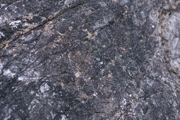 texture of a dark gray stone with white and yellow-orange splashes. Texture mountain close up. Background for wallpaper on the phone, computer with the texture of a stone mountain