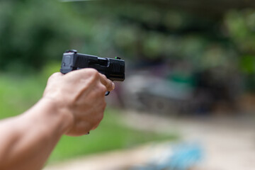 selective focus pistol in man's hand leaning forward in shooting range concept of violence Using guns in public areas, the rate of firearms.