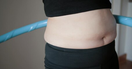 Close up of belly postpartum exercise with hula hoop, Overweight female twirling hula hoop, Fatty woman exercise for weight loss, slimming process, Slow motion - Powered by Adobe