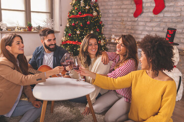 Friends singing Christmas songs and drinking wine