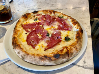 Pizza with bacon, pepperoni, melted cheese, olives served at Local Restaurant.