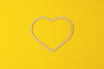 Cosmetic background with a wooden heart  on yellow. Flat lay, copy space