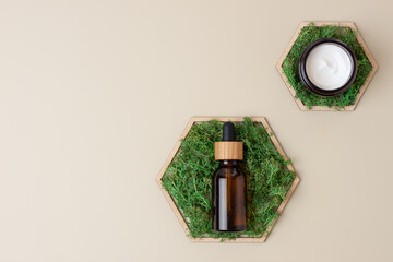 Cosmetic skin care products with a wooden hexagon and moss on pastel beige background. Flat lay, copy space