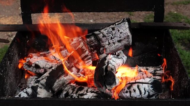 Firewood and coals burning in an iron barbecue