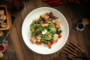 Mediterranean nitzard salad with roasted tuna on a wooden background