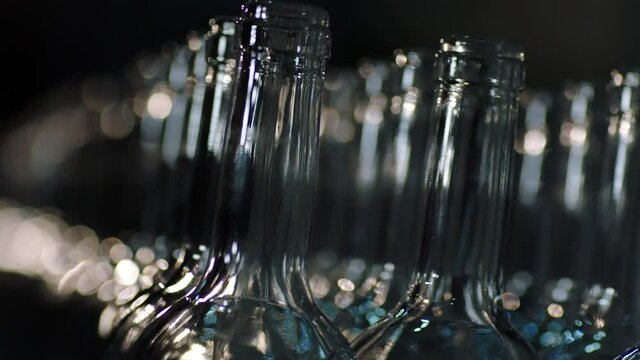 Many empty bottles for alcohol drinks on the table . Sorting bottles in wine factory . Close up view of row of red wine bottles . Shot on ARRI ALEXA Cinema Camera in slow motion .