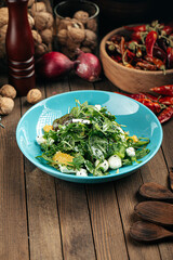Green salad with oranges and mozzarella cheese on the wooden background