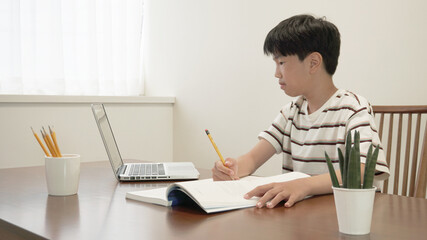 노트북을 보면서 공부하고 있는 소년 a boy looking at laptop while studying