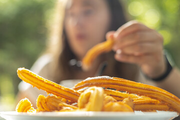 detail of flour churros with selective focus of a young girl having chocolate with churros for breakfast in a cafeteria