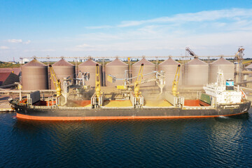 Loading grain into holds of sea cargo vessel through an automatic line in seaport from silos of grain storage. Bunkering of dry cargo ship with grain