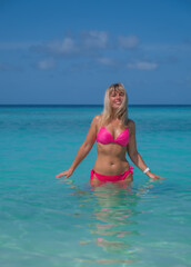 Fototapeta na wymiar Beautiful blond woman in pink bikini by blue lagoon. Crossroads Maldives, indian ocean. Saii lagoon hotel, july 2021