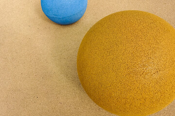 Close up of blue color stone grain textured half ball near the yellow ball on grain textured background. Reidi tee street, Tallinn, Estonia, Europe. June 2021