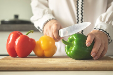 Chef preparing sweet pepper vegetable for salad or healthy food, modern kitchen background, sweet bell peppers on wooden board close-up