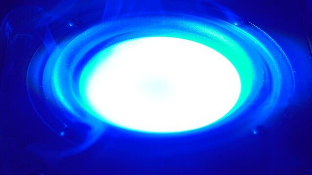 This stock video shows a close-up shot of a speaker emitting blue light and smoke