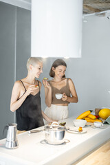 Lesbian couple have a breakfast together with avocado sandwich and coffee at modern kitchen. Homosexual relations and healthy eating in a comfortable home