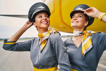 Stewardesses in pilot caps standing at the airdrome © Svitlana