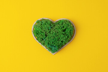 Cosmetic background with a wooden heart and moss on yellow. Flat lay, copy space