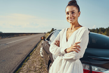 Female waiting beside her car with optimistic smile