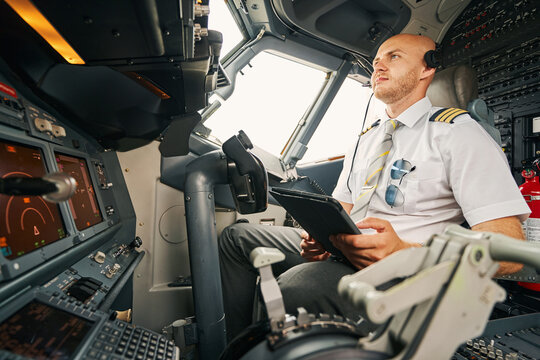Serious male pilot staring at the aircraft control panel