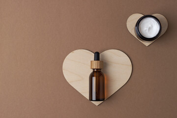 Cosmetic skin care products with a wooden heart on brown background. Flat lay, copy space