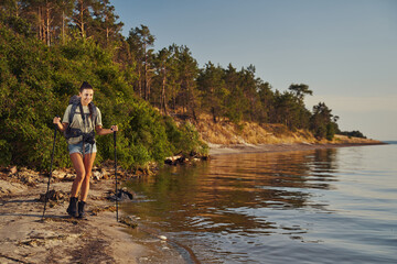Woman in T-shirt Nordic walking at riverbank