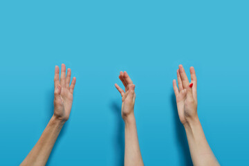 The hands of people faceless of Caucasians are raised up on a blue background.