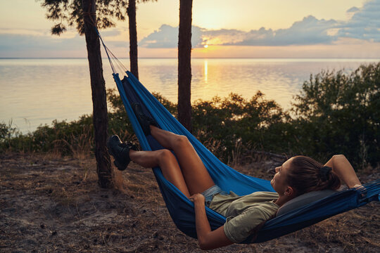 Tourist relaxing in hammock next to lakeside