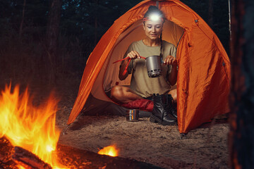Tourist using camping tableware for getting tea out of pot