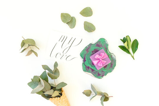 Resin art plate with gift box and paper card "My love" with eucalyptus on white. Top view
