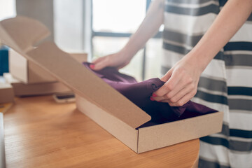 Experienced female worker packing garments before shipping