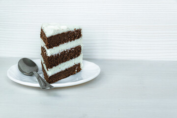 A teaspoon and a slice of buttercream chocolate sponge cake is located on the left