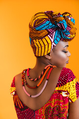 Bright clothes on black leather. The African woman turned her back to the camera and dressed in national clothes.
