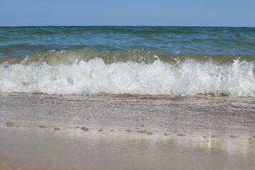 Sea waves roll on the sandy daytime beach