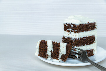 A fork and a piece of chocolate cream cake located on the right.