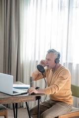 A gray-haired man in headphones having an audio conference online